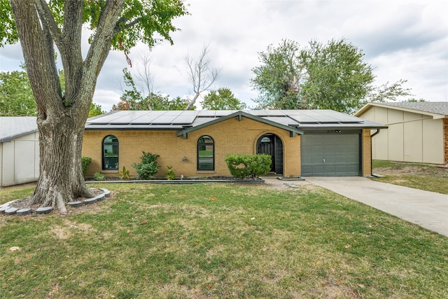 ranch-style home with a garage, solar panels, and a front yard