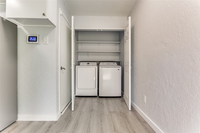 clothes washing area featuring light wood-type flooring, a textured ceiling, and washer and clothes dryer