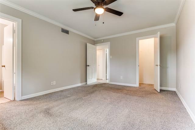 unfurnished bedroom with a walk in closet, ceiling fan, light colored carpet, and ornamental molding