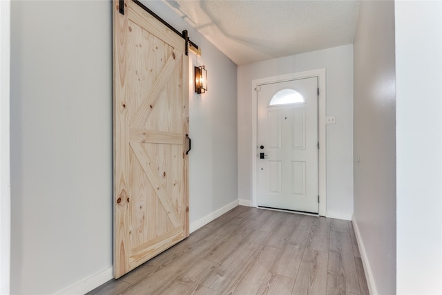 foyer entrance featuring a textured ceiling, a barn door, and light hardwood / wood-style flooring