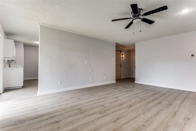 interior space featuring a textured ceiling, light hardwood / wood-style flooring, ceiling fan, and a barn door