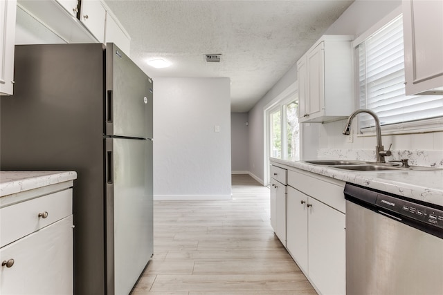 kitchen featuring a textured ceiling, sink, stainless steel appliances, and white cabinets