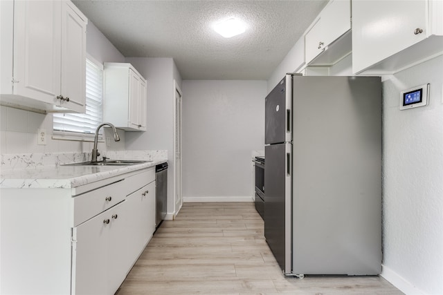 kitchen featuring a textured ceiling, stainless steel appliances, sink, light wood-type flooring, and white cabinets