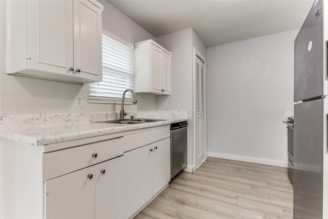 kitchen featuring light wood-type flooring, stainless steel appliances, white cabinetry, sink, and a textured ceiling