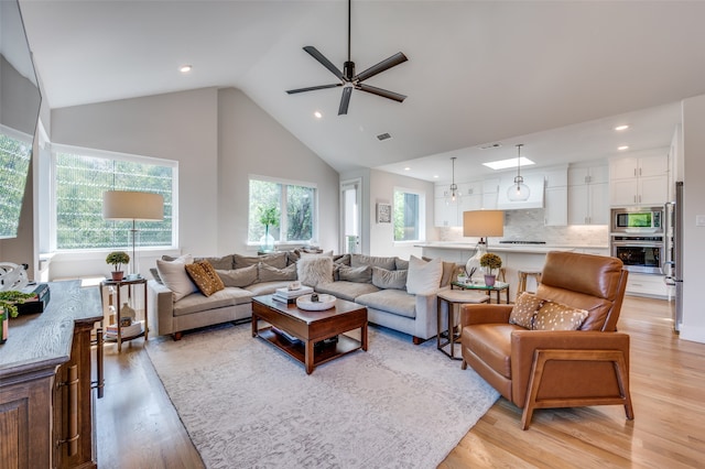 living room featuring high vaulted ceiling, light wood-type flooring, and ceiling fan