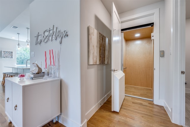 hallway with light hardwood / wood-style floors and elevator