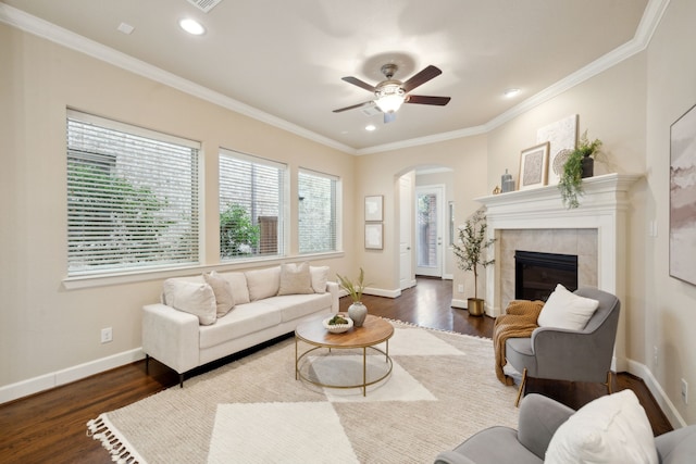 living room featuring ceiling fan, a tile fireplace, dark hardwood / wood-style flooring, and ornamental molding