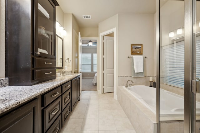 bathroom featuring vanity, a relaxing tiled tub, and tile patterned floors