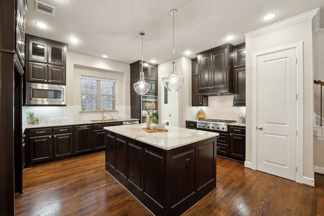 kitchen featuring dark hardwood / wood-style flooring, a kitchen island, sink, light stone countertops, and appliances with stainless steel finishes