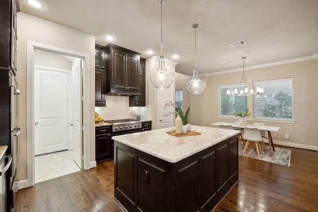 kitchen with an inviting chandelier, decorative light fixtures, dark wood-type flooring, a kitchen island, and decorative backsplash