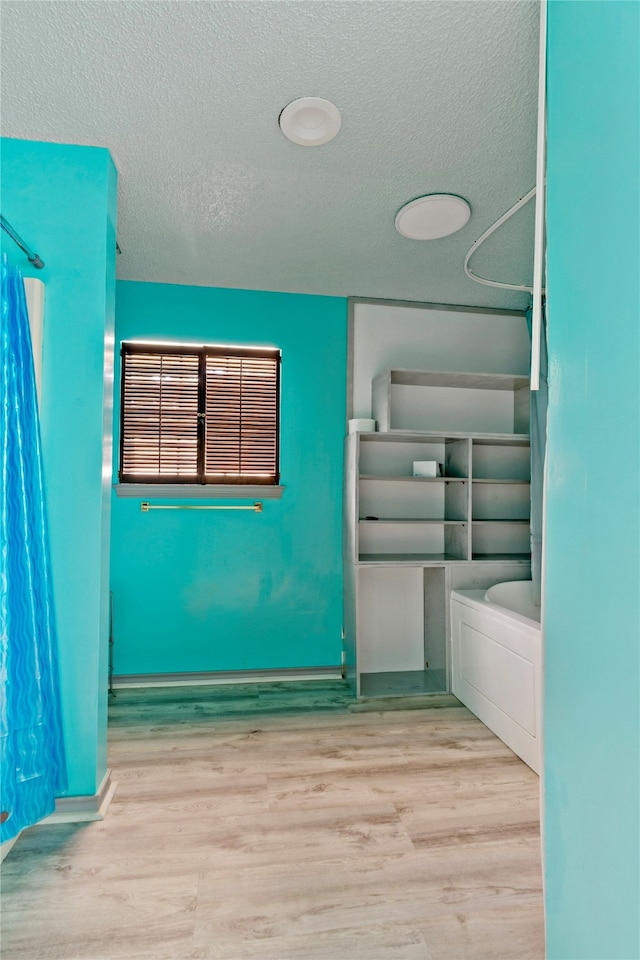 interior space featuring a textured ceiling, a shower with shower curtain, and hardwood / wood-style flooring