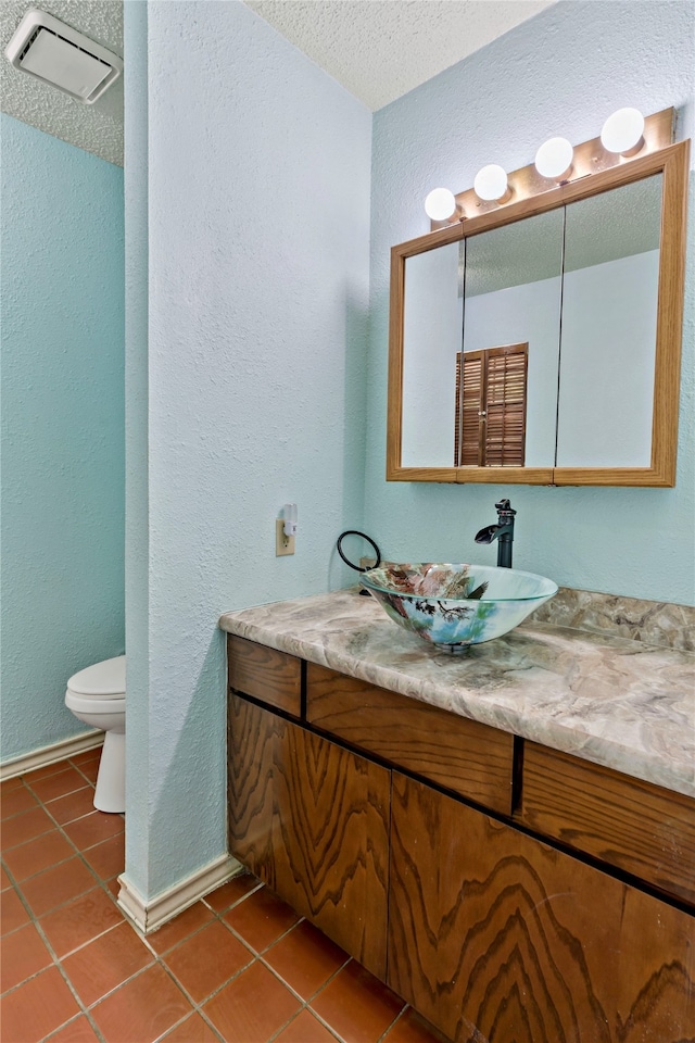 bathroom featuring a textured ceiling, vanity, toilet, and tile patterned flooring