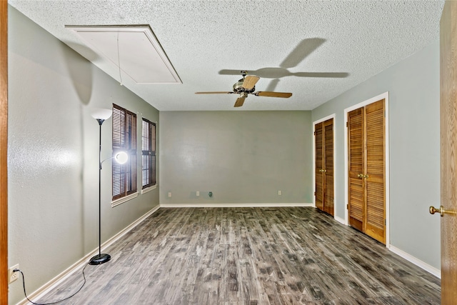 unfurnished bedroom featuring multiple closets, dark hardwood / wood-style flooring, ceiling fan, and a textured ceiling