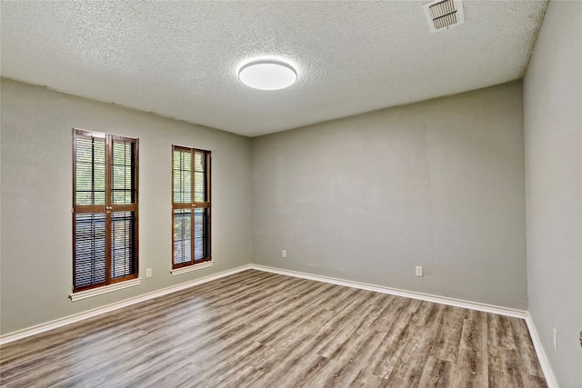 unfurnished room with hardwood / wood-style flooring and a textured ceiling