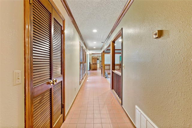 corridor featuring light tile patterned floors, crown molding, and a textured ceiling