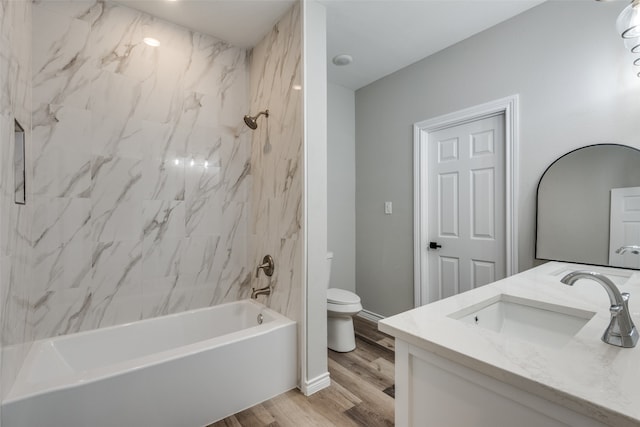 full bathroom featuring wood-type flooring, toilet, tiled shower / bath combo, and vanity