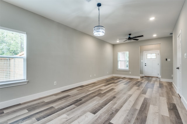 interior space with ceiling fan with notable chandelier and light hardwood / wood-style flooring