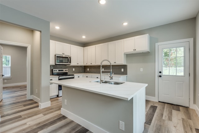 kitchen with light wood-type flooring, sink, appliances with stainless steel finishes, and white cabinets