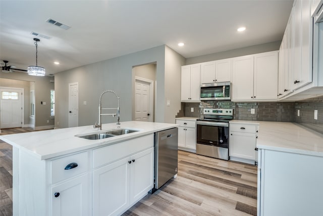 kitchen featuring white cabinets, appliances with stainless steel finishes, sink, ceiling fan, and a kitchen island with sink