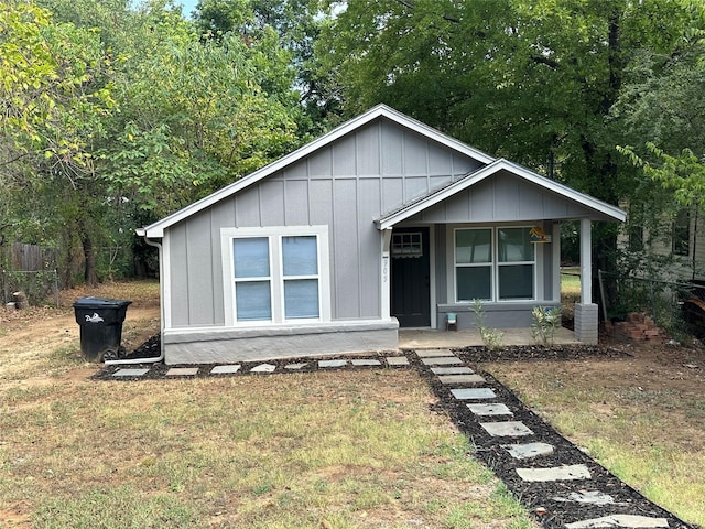 bungalow with a front lawn, board and batten siding, and fence