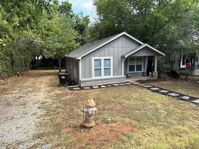 view of front of property with driveway, fence, a front lawn, and board and batten siding