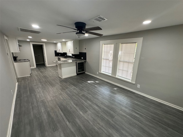 interior space featuring white cabinets, dark hardwood / wood-style floors, kitchen peninsula, beverage cooler, and ceiling fan