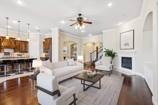 living room featuring ceiling fan, dark hardwood / wood-style flooring, and crown molding