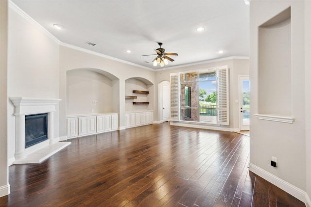 unfurnished living room with built in shelves, ceiling fan, ornamental molding, and dark wood-type flooring