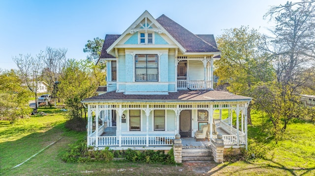 victorian house featuring a porch and a front lawn