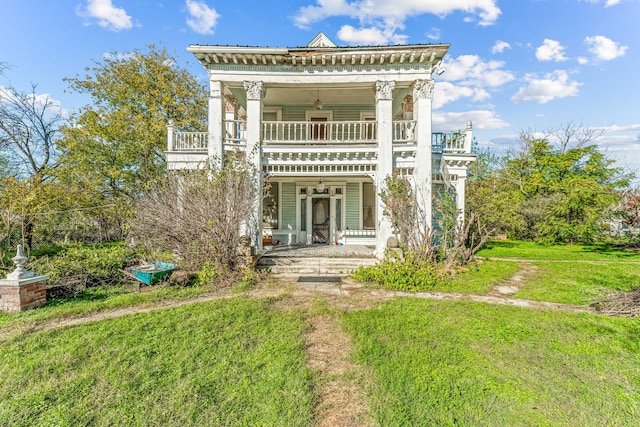 back of house with a balcony, ceiling fan, a porch, and a yard