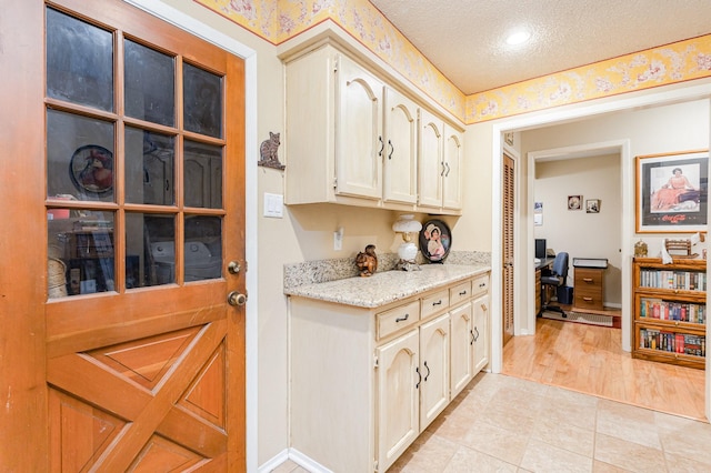 kitchen with light stone countertops, a textured ceiling, and light hardwood / wood-style flooring