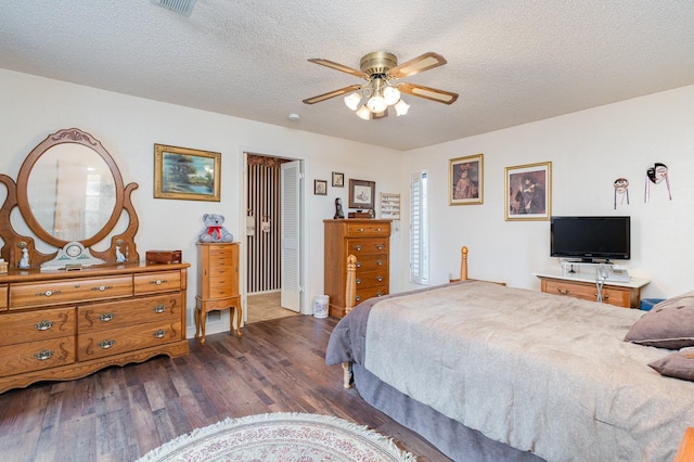 bedroom featuring a textured ceiling, a closet, ceiling fan, and dark wood-type flooring