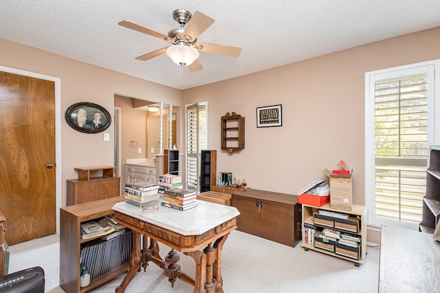 office featuring light carpet, a textured ceiling, and ceiling fan