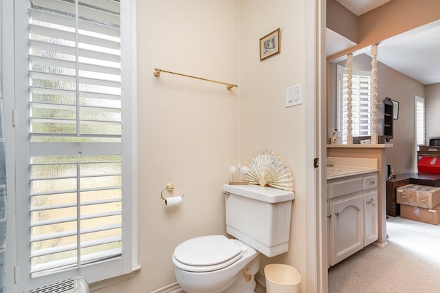 bathroom with plenty of natural light, toilet, a textured ceiling, and vanity