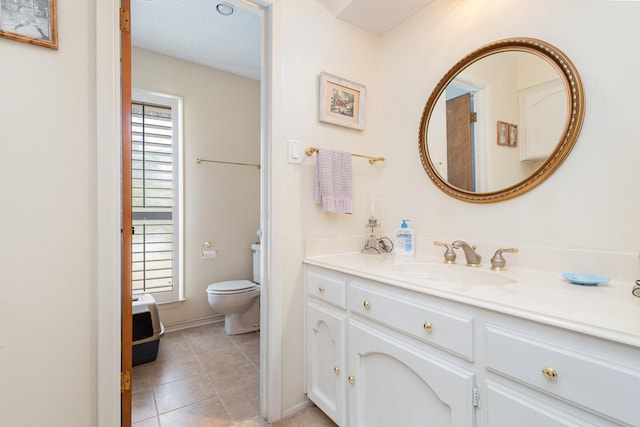 bathroom with plenty of natural light, toilet, a textured ceiling, and vanity