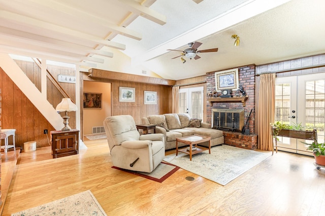 living room featuring hardwood / wood-style floors, wood walls, french doors, lofted ceiling with beams, and ceiling fan