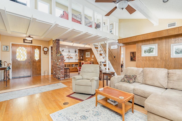 living room featuring wood walls, high vaulted ceiling, ceiling fan, beamed ceiling, and wood-type flooring