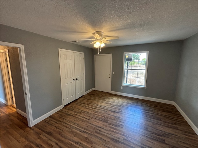 unfurnished bedroom with a textured ceiling, ceiling fan, and dark hardwood / wood-style floors