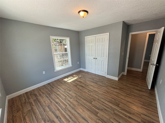 unfurnished bedroom with a textured ceiling, dark wood-type flooring, and a closet