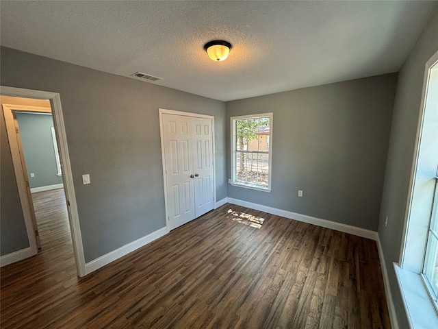 unfurnished bedroom featuring dark wood-type flooring, a closet, and a textured ceiling