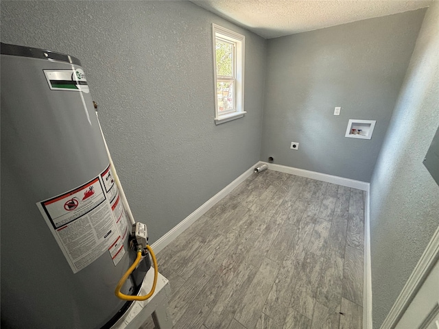 clothes washing area with gas water heater, hardwood / wood-style flooring, electric dryer hookup, washer hookup, and a textured ceiling