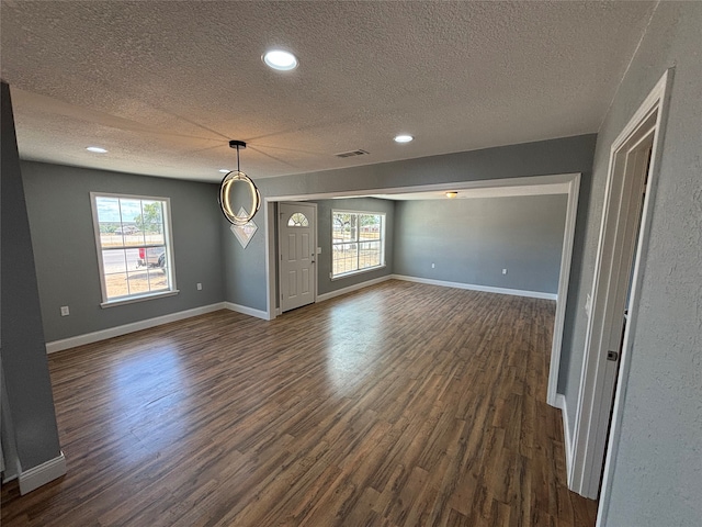 interior space with dark wood-type flooring, a textured ceiling, and a healthy amount of sunlight