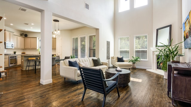 living room featuring dark wood-type flooring, a wealth of natural light, and a high ceiling