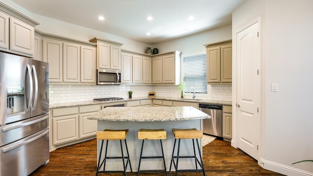 kitchen with backsplash, a kitchen bar, a kitchen island, dark wood-type flooring, and appliances with stainless steel finishes