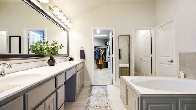 bathroom featuring lofted ceiling, vanity, tile patterned floors, and a washtub