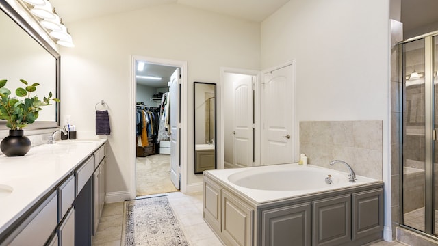 bathroom with tile patterned flooring, separate shower and tub, vaulted ceiling, and vanity