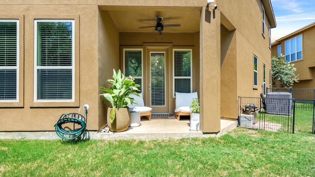 entrance to property with a lawn, ceiling fan, a patio, and central AC