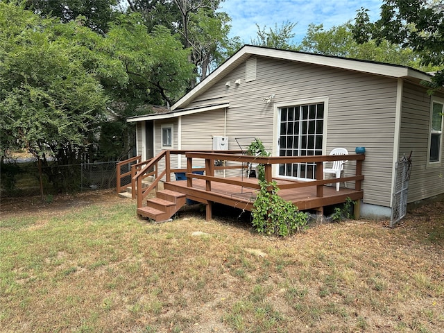 rear view of property with a wooden deck and a lawn