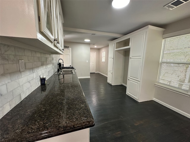 kitchen with dark stone countertops, sink, decorative backsplash, dark wood-type flooring, and white cabinets