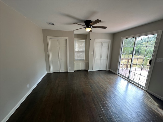 unfurnished bedroom featuring two closets, ceiling fan, dark hardwood / wood-style floors, and access to outside